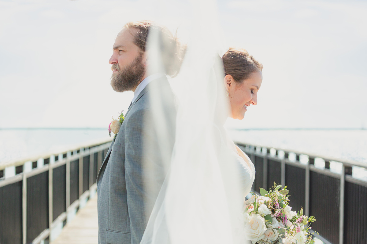 bride and groom stand back to back on gallagher pier at the Outer Harbor in Buffalo, NY