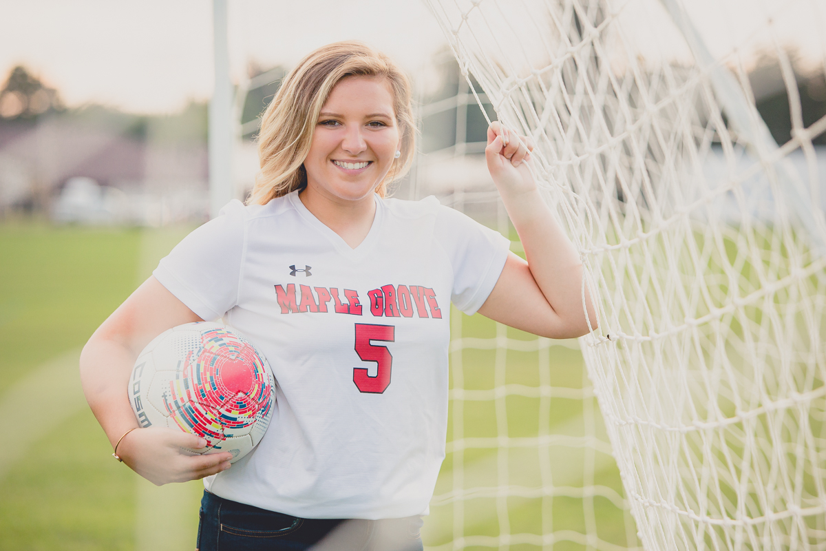 senior portrait by photographer Lindsay DeDario of maple grove high school student leaning on soccer net while holding ball in Bemus Point, a small town near Buffalo, NY in WNY 