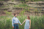 couple holds hands and smiles at each other on trail during wedding engagement portrait photography session at Artpark in Lewiston, NY