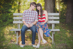 future groom and bride sit together on park bench during wedding engagement photography session in Buffalo, NY