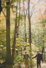 engaged couple holds hands and walks in woods during engagement photography session near Ellicottville, NY