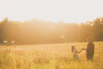 engagement photography of couple around sunset as the groom picks the bride a flower in field at Knox Farm State Park in East Aurora, NY outside of Buffalo, NY