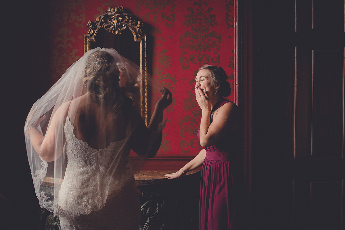 maid of honor bridesmaid cries while looking at bride getting ready in mirror before wedding at Statler City in Buffalo, NY
