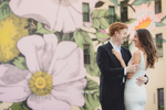bride and groom laugh while embracing in front of the {quote}wildflowers for Buffalo{quote} mural in downtown Buffalo, NY during their wedding engagement portrait photography session