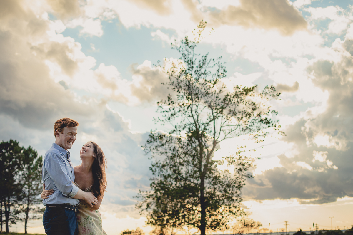 bride and groom laugh during sunset in field at Tifft Nature Preserve in Buffalo, NY during their wedding engagement photography session