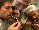 Three men huddle in a corner to smoke heroin away from the crowds and vendors of the Old Bazaar in Peshawar. Inhaling the smoke is known as {quote}chasing the dragon.{quote} In the city of 300,000 there are 40,000 heroin users with Afghanistan supplying the drug. 