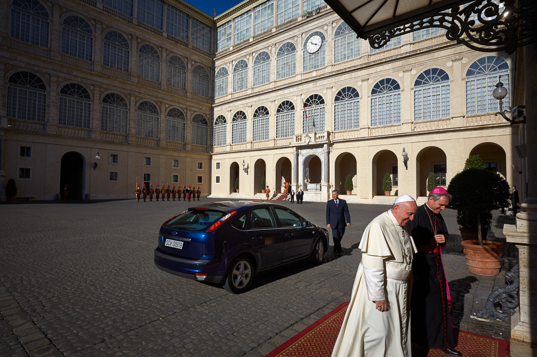 Pope Francis arrives at the Apostolic Palace in Vatican City for an appointment with a foreign dignitary. Behind him is the small blue Ford Focus he is known to travel to appointments in.