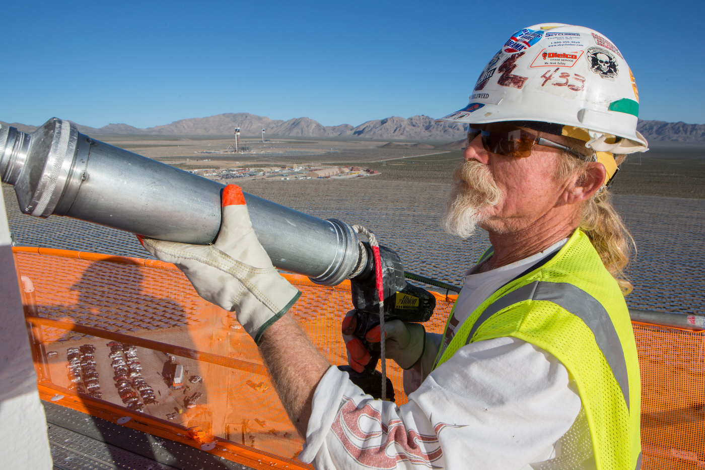 IVANPAH, CALIFORNIA, OCTOBER 18 2012: Iron Worker {quote}Tumblewwed{quote} apples caulking to the white panels atop Tower 1, with Tower 2 and 3 visible in the background at the Ivanpah Solar Project (photo Gilles Mingasson/Getty Images for Bechtel).