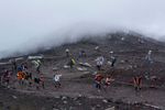 Surrounded by rolling clouds, hikers walk up on the Yoshida trail, a Mount Fuji's most popular route.
