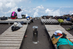 Exhausted hikers rest on wooden benches after reaching Mount Fuji's 13,389 ft summit.