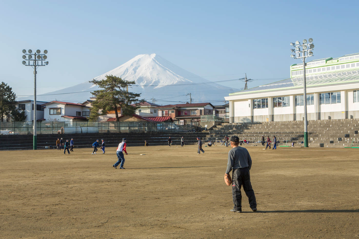Retirees play baseball with Mt. Fuji as a backdrop.