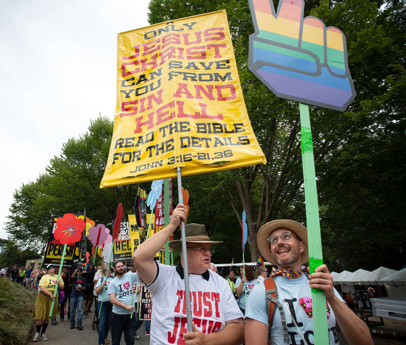 Atlanta, GA, Oct. 12, 2019 --  A volunteer member of the 'Pansy Patrol' takes delight in obscuring a sign held by one of a group of street and open air preachers who yell insults and obscenities to attendees of the city's Gay Pride Parade.(AP Photo/Robin Rayne)