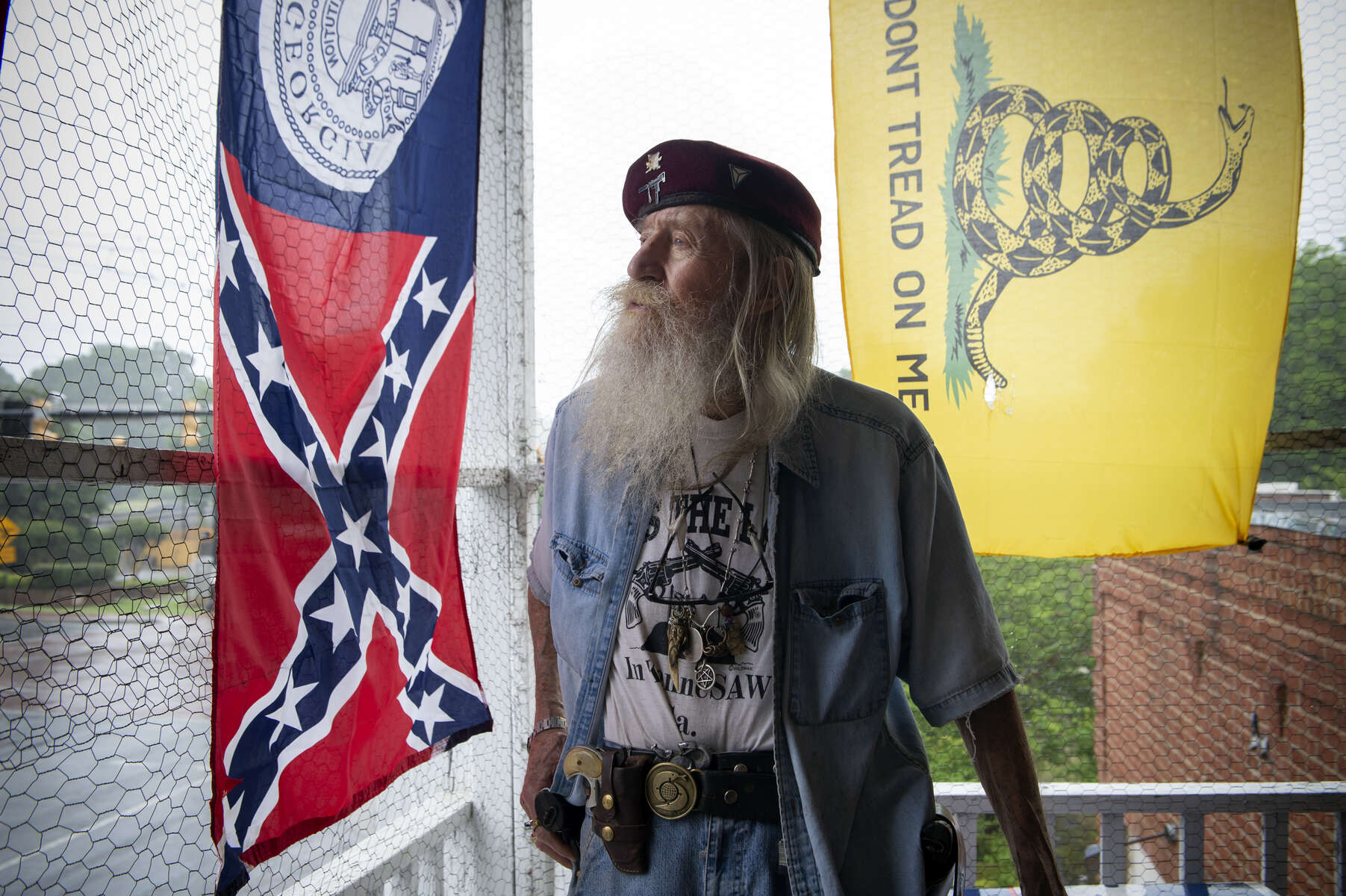 A group of angry demonstrators gathered outside Dent Myers’ Civil War Relic and Antique Shop Friday to protest the 89-year-old owner’s obsession with what they see as a racist and bigoted past. Pictured: Dent Myers on top floor of building that houses his relic shop, keeping an eye on gathering protesters.