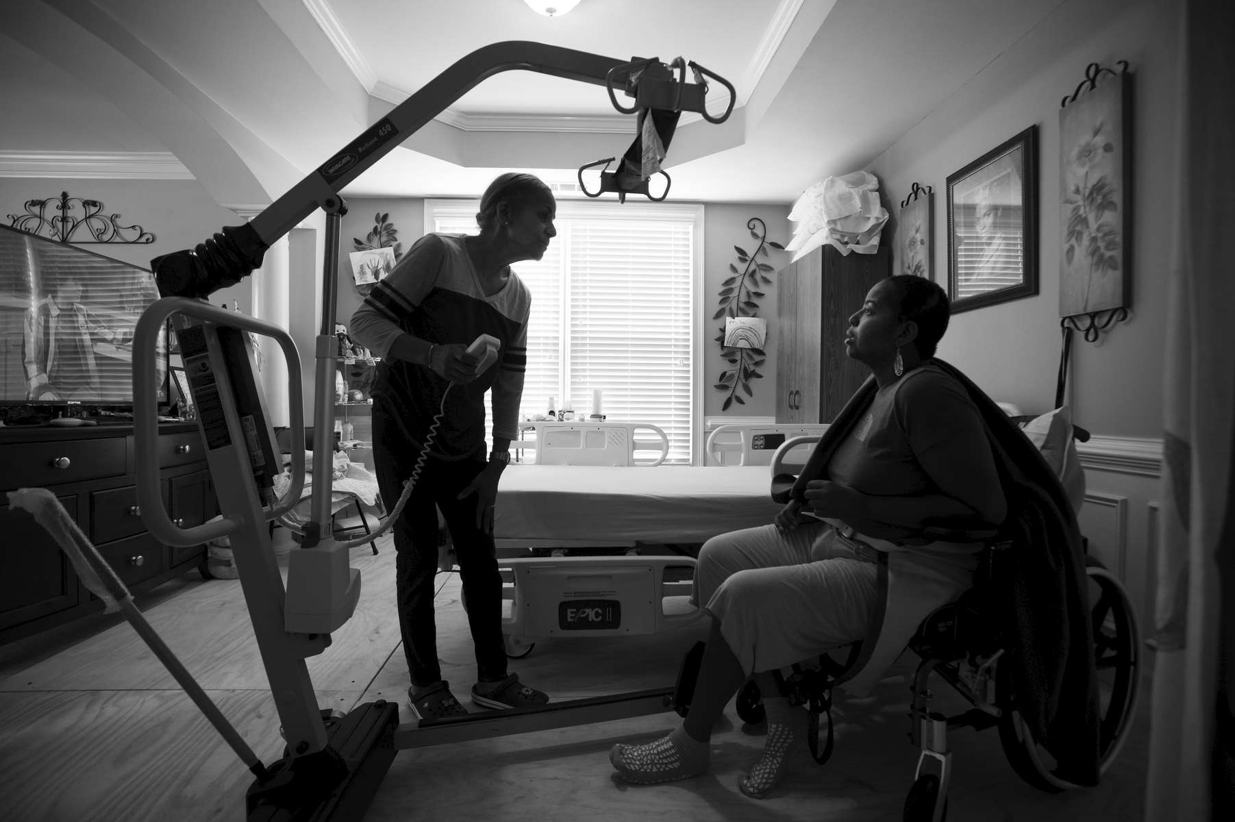 Erika Jones, 32,  is on the slow path to recovery from a brain tumor that left her paralyzed and unable to speak more than a few words. Her mother Joyce Jones insisted she be moved back into her family's home rather than a nursing facility. {quote}I am committed to caring for my baby until the day I die,{quote} Joyce explained. {quote}She wouldn't get that love in a nursing home.{quote} Pictured: Joyce Jones chats with Erika in what was once family dining room, now converted to Erika's room on the ground floor. The electric lift used to move Erika from bed to chair was donated by a local rehabilitation hospital.