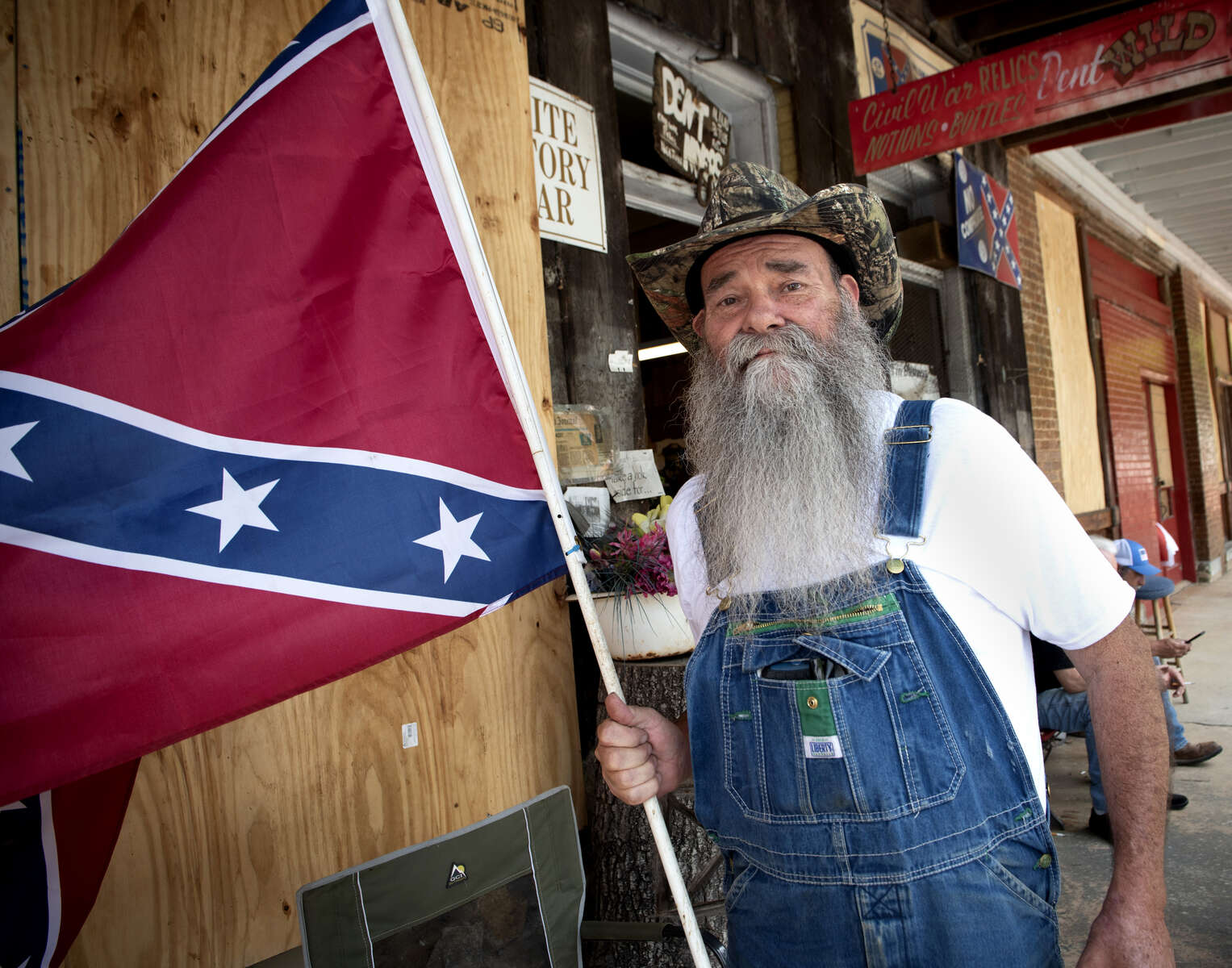 LAMARR MAYES, 64, from Fairmount, GA, holds his personal Confederate Battle Flag replica outside Dent Myers’ Civil War Surplus store, where regular visitors often meet to share their views on society with others who appreciate ways of the ‘Old South.’