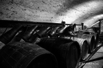 black and white photograph of 5 barrels on a rack, several large jugs to distribute the wine and bellows to help fill the jugs