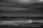 A moody sky and a croft lit by a patch of sunlight in black and white