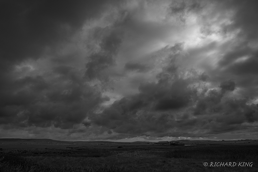 Dark skies, sun trying to get through over moorland
