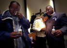 Kenny McClellan, grandfather Christopher Thomas, Jr., (left) wipes his tears as his daughter Shantrina Freeman, 12, (center) is comforted by minister Gregory Lewis, (right) following a candlelight vigil held for Christopher Thomas, Jr. Signs of violent child abuse were not recognized by the child's caseworker, and Thomas died of injuries after a severe beating.