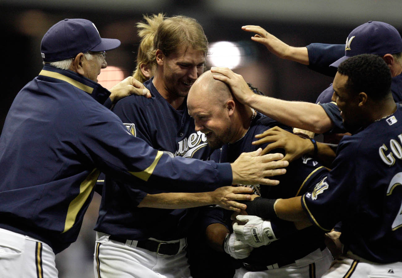 Casey McGehee is surrounded with teammates, including coach Ken Macha (left) after McGehee came up with a hit in the bottom of the 9th inning, on a full count, that scored two runs to give the Brewers the win over the Cubs.