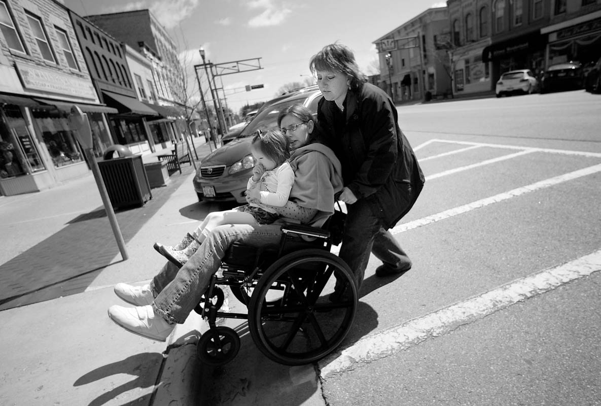 Juli Henrie, right, wheels her sister Courtney Johnson-Atherden, center, over a curb in Lake Geneva, April 5, 2007. Juli's daughter Brinn, 4, rides on her aunt's lap. Juli brought her sister home to live with her and says although Courtney needs a lot of care, the decision was easy. Nearly all of Courtney's memory has been erased, but one person she did not forget was her favorite sister, Juli.