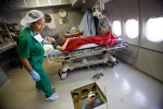 Most of the surgeries and procedures are aboard the Flying Eye Hospital, a DC-10 that has been retrofitted with full surgery capabilities. ORBIS's Troy Ingham, RN, climbs through the floor of the recovery room, bringing up supplies from the storage area as patient Yeth Oen awaits surgery.