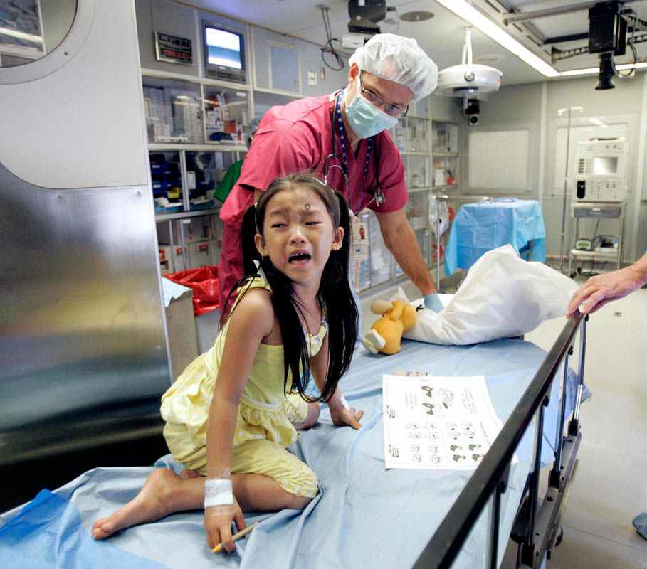 As volunteer anesthesiologist Dr. Artem Grush wheels Line Chea, 5, into the operation room for her surgery, she turns back and cries for her mother, aboard the ORBIS Flying Eye Hospital. Line was the first surgery performed for the 100th trip of the plane, and the first of the program in Cambodia. 