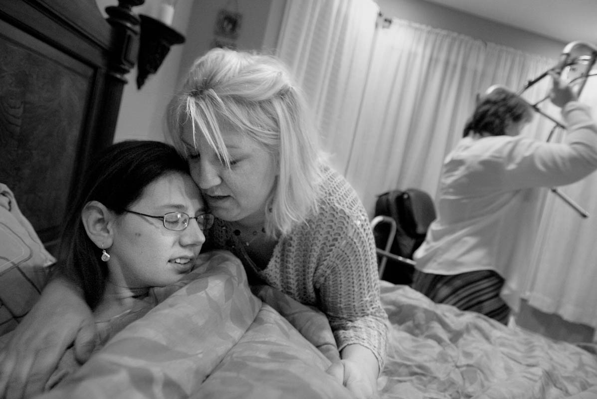 Courtney is tucked into bed by her sister-in-law Angie Johnson, center, as Juli picks up Courtney's room and prepares for another day.