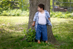 Izzy hides behind a tree while playing at home in May. Two years after the child declared 'I boy,' the parents began to socially transition her to living as a boy.