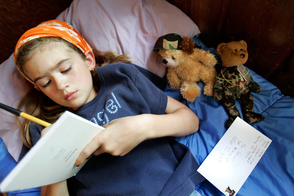 Veronica Sherman,9, of DeKalb, IL, writes her father a letter, with her camouflage bear wearing dog tags nearby. The bear was a gift from her father before he deployed to Iraq and it's never far from Veronica's hands.