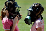 Two children chat while wearing gas masks During Operation Purple camp. The camp was designed to give military children a place to interact with one another and discuss having parents who are in Iraq. At this event, kids could try on gas masks, helmets, flak jackets, and other equipment used by members of the military.