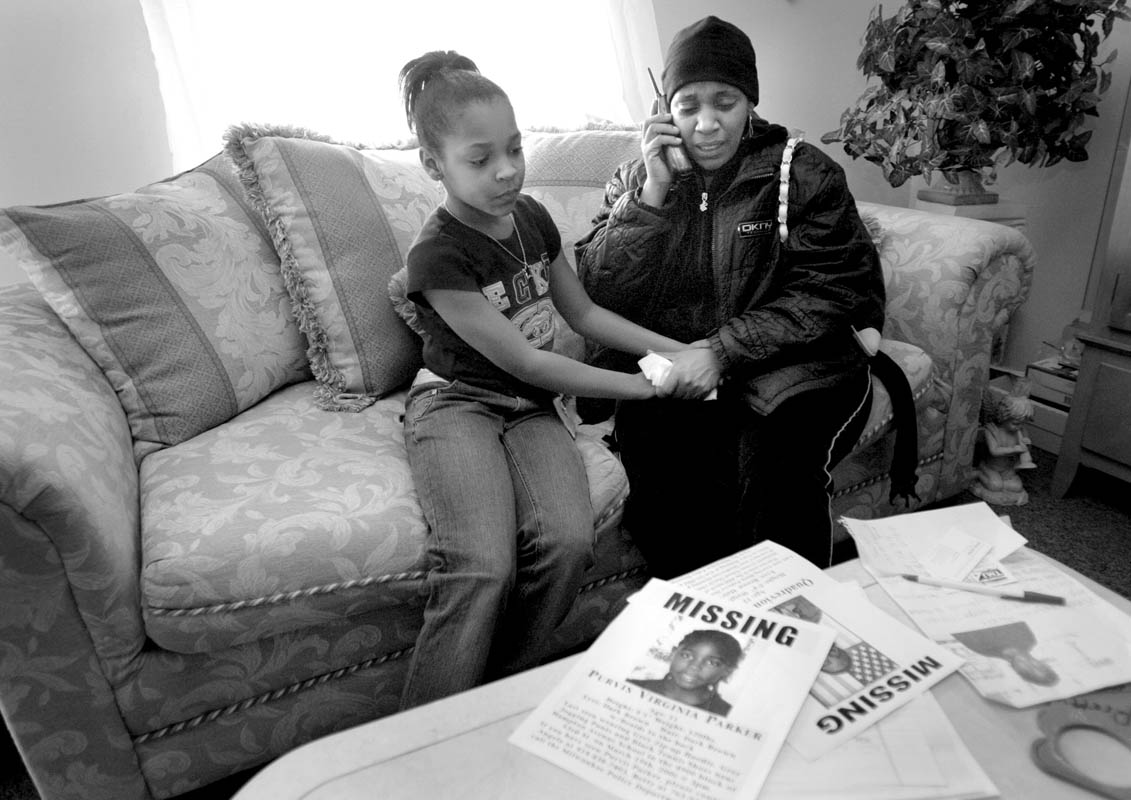 Shymeka Brown, 9, left, comfrots her mother Angela Virginia, right, at their Milwaukee home, as Angela updates relatives about the search for Purvis.