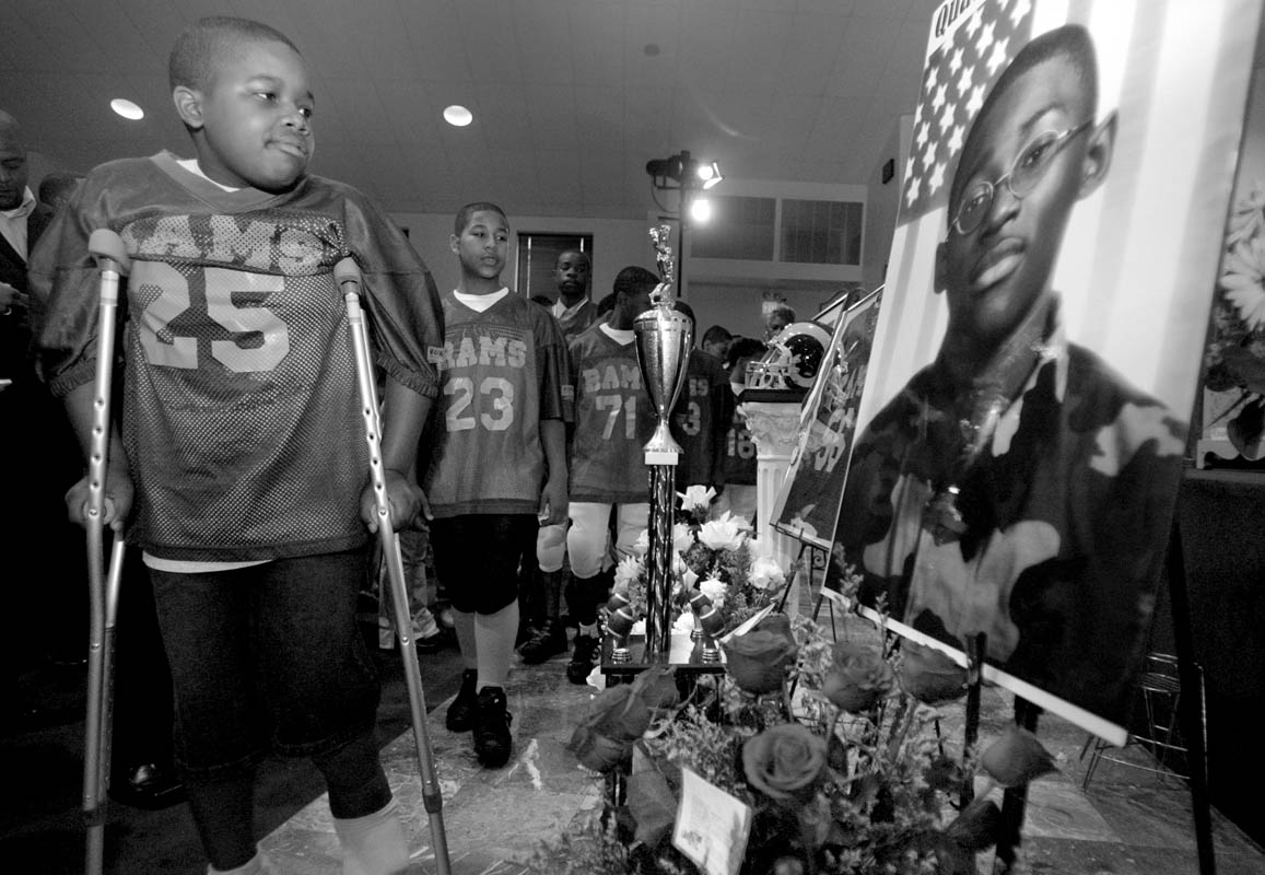 Members of the Neighborhood Center Sports League Mighty Rams team file past Quadrevion's photos at the start of his funeral services. Quadrevion played on the team for three years.