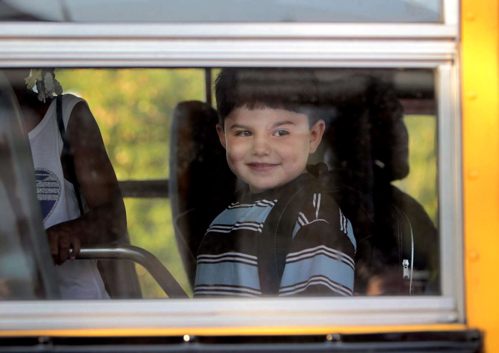 Izzy boards a school bus on his first day of school, smiling out the window at his mother. Jennifer has signed the child up as a male, and has been working with the school district to educate them on transgender issues and been very happy with the reception so far.