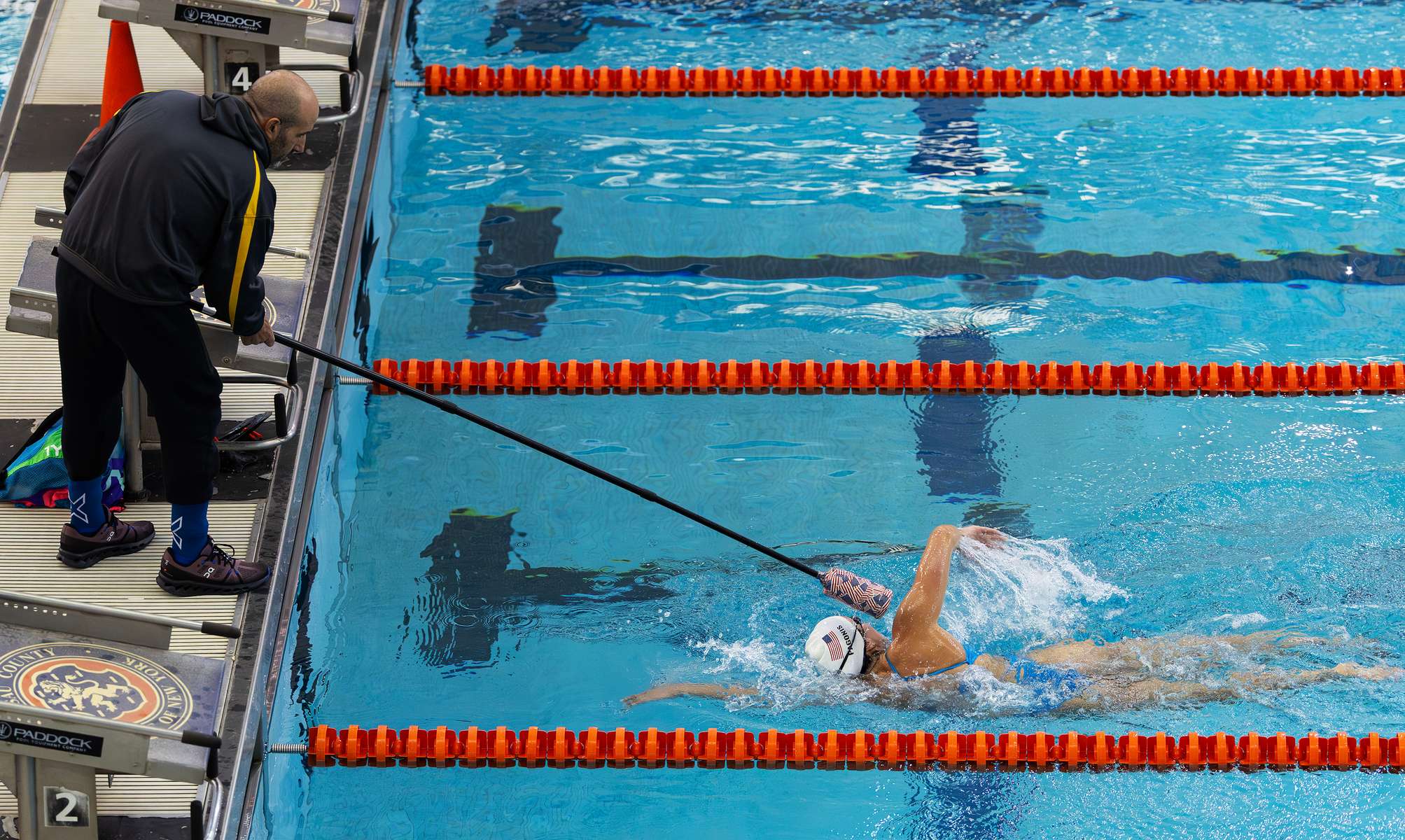 United States Paralympian Anastasia Pagonis is tapped on the head by her coach Darryn Solotoff during a training session at Nassau County Aquatic Center on May 25, 2024 in East Meadow, New York.  Pagonis has autoimmune retinopathy which led her sight to decrease at the age of 11, and she lost her vision by the age of 14.  She competed in the swimming competition at the Tokyo 2020 Paralympic Games where she won a gold and bronze medal respectively in the 400m Freestyle S11 and 200-meter Individual Medley S11.  An S11 athlete is the most severe form of visual impairment. S11 swimmers all swim with blacked-out goggles to ensure a level playing field, blocking out all light so it's like swimming with a blindfold.  This is why they typically swim on the lane line and have tappers to inform them when they need to turn or stop.  She will be competing in the 400m Freestyle S11 at the 2024 Paralympic Games this summer in Paris, France. 