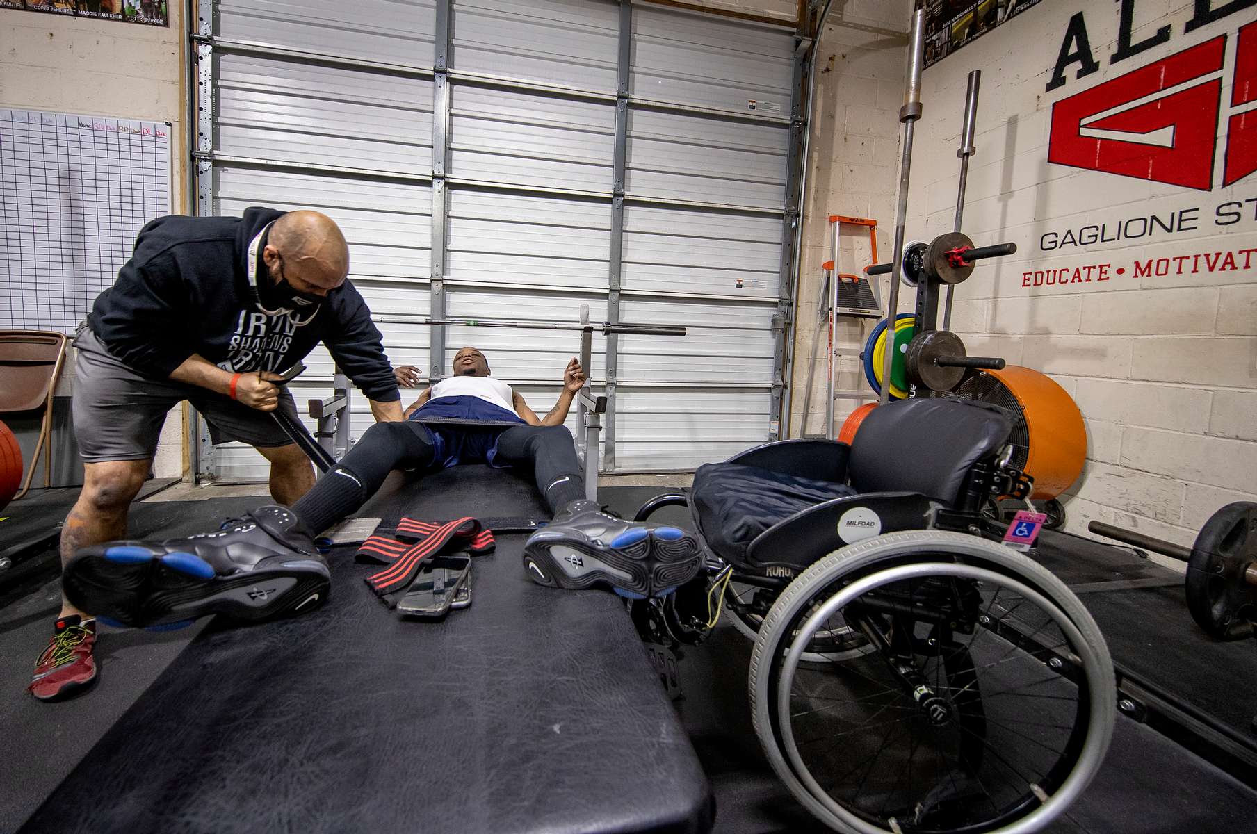 Team USA Para Powerlifter Garrison Redd has his legs strapped to the the bench to secure his legs by his Strength and conditioning coach John Gaglione.  Redd is preparing for a bench press training session at Gaglione Strength Gym on April 07, 2021 in Farmingdale, New York.