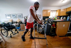 Team USA Para Powerlifter Garrison Redd is upright wearing Kafo Leg braces, as he walks in his home using his upper body strength, and the assistance of a walker on October 25, 2021 in Brooklyn, New York.  