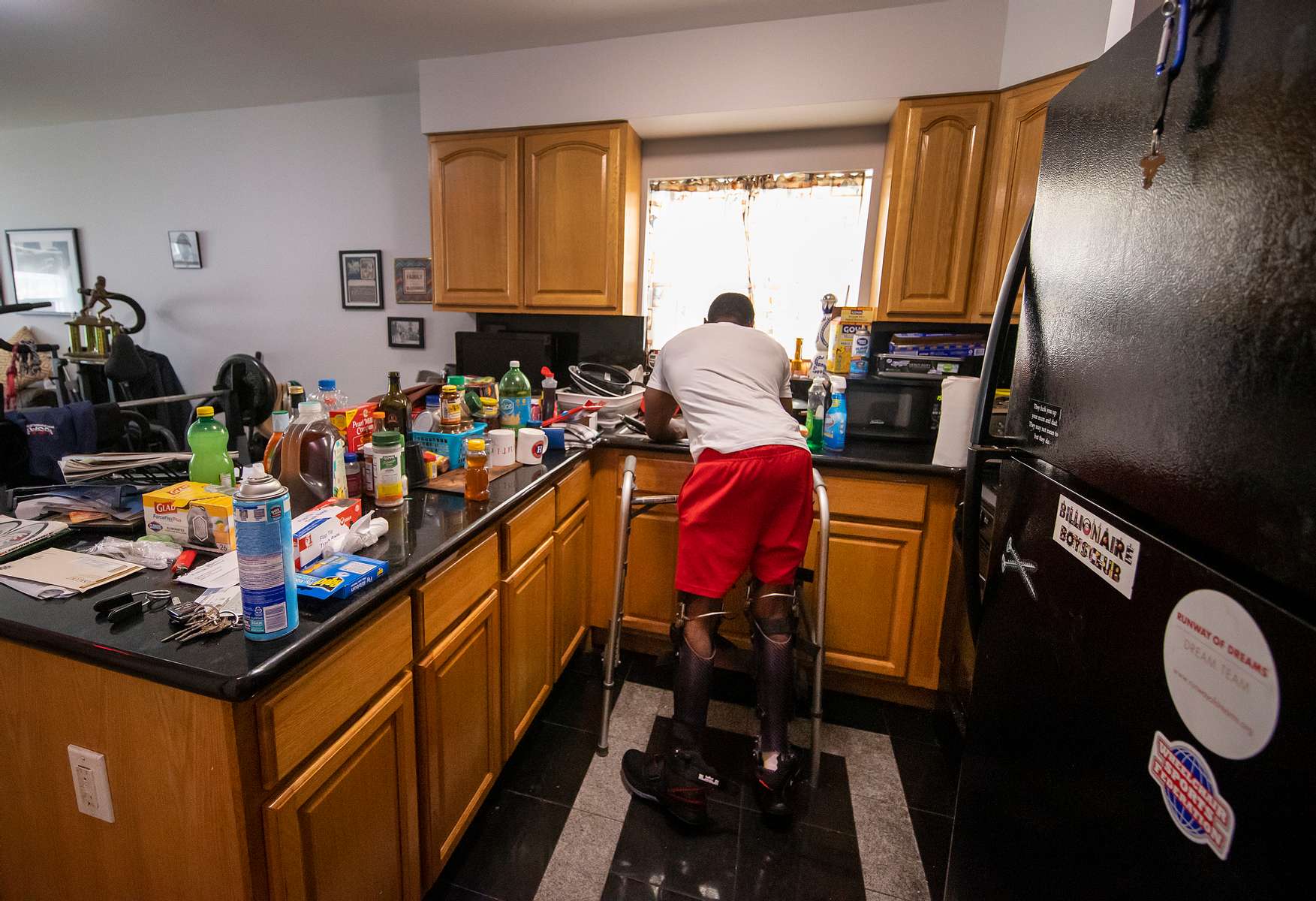Team USA Para Powerlifter Garrison Redd is wearing Kafo Leg braces, as he holds himself up using his upper body strength, and the assistance of a walker while washing the dishes in his home on October 25, 2021 in Brooklyn, New York. 