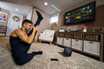 Dennis Guerrero, who is the Co-owner, and Head Trainer of Life Outside the Box fitness leads a virtual exercise class from his living room on November 8th, 2020 in Long Beach, New York. In March of 2014, Dennis Guerrero and his business partner opened a gym on Long Island. The pair shared a passion for fitness, a dream of creating a local community of like-minded people and a willingness to take a risk. Over the next six years, hundreds of members experienced and embraced a unique environment that fostered a palpable energy, helping athletes of all ages and abilities reach their potential.  The gym became a place to share achievements, work through losses and overcome illness. But like so many other businesses, it seemingly had no way of overcoming the financial impact and ongoing uncertainty of a global pandemic. With the arrival of Covid-19, the gym shut its doors back in March, with no idea when it would reopen. The owners, though, were far from done. They lent out every piece of equipment they owned to the gym’s members, continued to pay their staff and worked to set up outdoor classes in hopes of keeping their membership active and healthy. As the shutdown stretched on, it became clear that the physical gym was closed for good.  They have since reinvented themselves and are now called Life Outside the Box.  Their business model has changed drastically, and all their workouts have gone virtual.  The workouts are conducted by a small group of fitness trainers led by Guerrero.  The members pay a monthly fee and can take live Zoom fitness classes.  They are coached by the virtual trainers in real time.  More and more people have reconstructed their garages, spare rooms, backyards, and basements into home gyms since the COVID-19 pandemic hit the United States.  