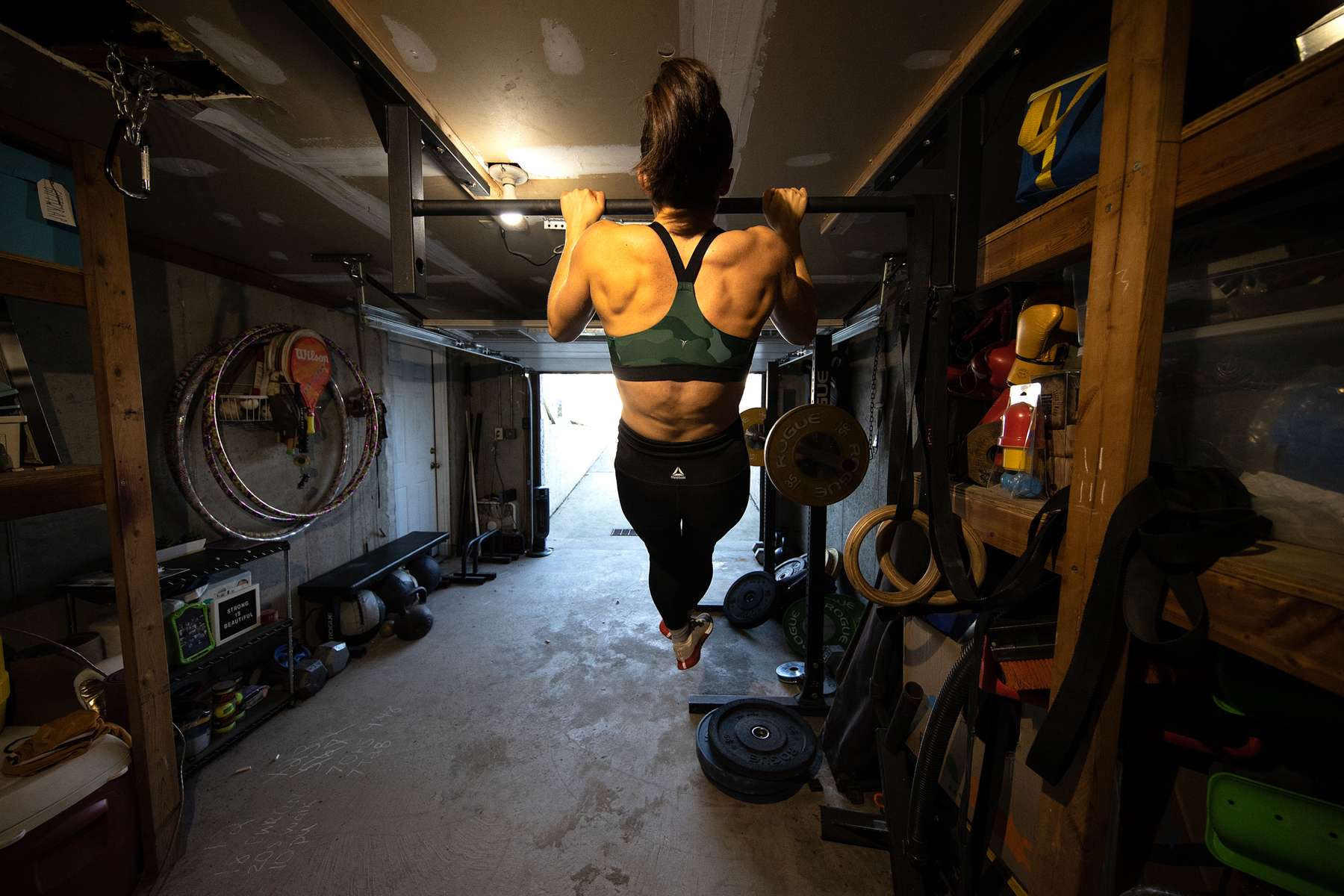 Nicole Guerrero exercises in her garage with her virtual Fitness Trainer and Husband Dennis Guerrero on November 21st, 2020 in Long Beach, New York. In March of 2014, Dennis Guerrero and his business partner opened a gym on Long Island. The pair shared a passion for fitness, a dream of creating a local community of like-minded people and a willingness to take a risk. Over the next six years, hundreds of members experienced and embraced a unique environment that fostered a palpable energy, helping athletes of all ages and abilities reach their potential.  The gym became a place to share achievements, work through losses and overcome illness. But like so many other businesses, it seemingly had no way of overcoming the financial impact and ongoing uncertainty of a global pandemic. With the arrival of Covid-19, the gym shut its doors back in March, with no idea when it would reopen. The owners, though, were far from done. They lent out every piece of equipment they owned to the gym’s members, continued to pay their staff and worked to set up outdoor classes in hopes of keeping their membership active and healthy. As the shutdown stretched on, it became clear that the physical gym was closed for good.  They have since reinvented themselves and are now called Life Outside the Box.  Their business model has changed drastically, and all their workouts have gone virtual.  The workouts are conducted by a small group of fitness trainers led by Guerrero.  The members pay a monthly fee and can take live Zoom fitness classes.  They are coached by the virtual trainers in real time.  More and more people have reconstructed their garages, spare rooms, backyards, and basements into home gyms since the COVID-19 pandemic hit the United States. 