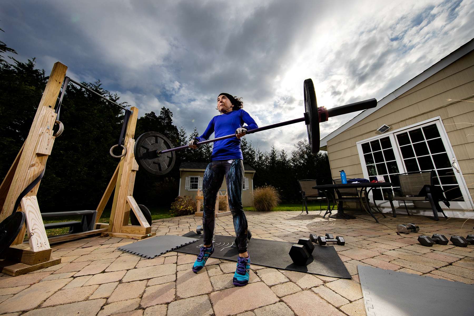 Debbie Krueger exercises in her backyard with her virtual Fitness Trainer Dennis Guerrero on November 17th, 2020 in Hewlett Harbor, New York.  In March of 2014, Dennis Guerrero and his business partner opened a gym on Long Island. The pair shared a passion for fitness, a dream of creating a local community of like-minded people and a willingness to take a risk. Over the next six years, hundreds of members experienced and embraced a unique environment that fostered a palpable energy, helping athletes of all ages and abilities reach their potential.  The gym became a place to share achievements, work through losses and overcome illness. But like so many other businesses, it seemingly had no way of overcoming the financial impact and ongoing uncertainty of a global pandemic. With the arrival of Covid-19, the gym shut its doors back in March, with no idea when it would reopen. The owners, though, were far from done. They lent out every piece of equipment they owned to the gym’s members, continued to pay their staff and worked to set up outdoor classes in hopes of keeping their membership active and healthy. As the shutdown stretched on, it became clear that the physical gym was closed for good.  They have since reinvented themselves and are now called Life Outside the Box.  Their business model has changed drastically, and all their workouts have gone virtual.  The workouts are conducted by a small group of fitness trainers led by Guerrero.  The members pay a monthly fee and can take live Zoom fitness classes.  They are coached by the virtual trainers in real time.  More and more people have reconstructed their garages, spare rooms, backyards, and basements into home gyms since the COVID-19 pandemic hit the United States.  