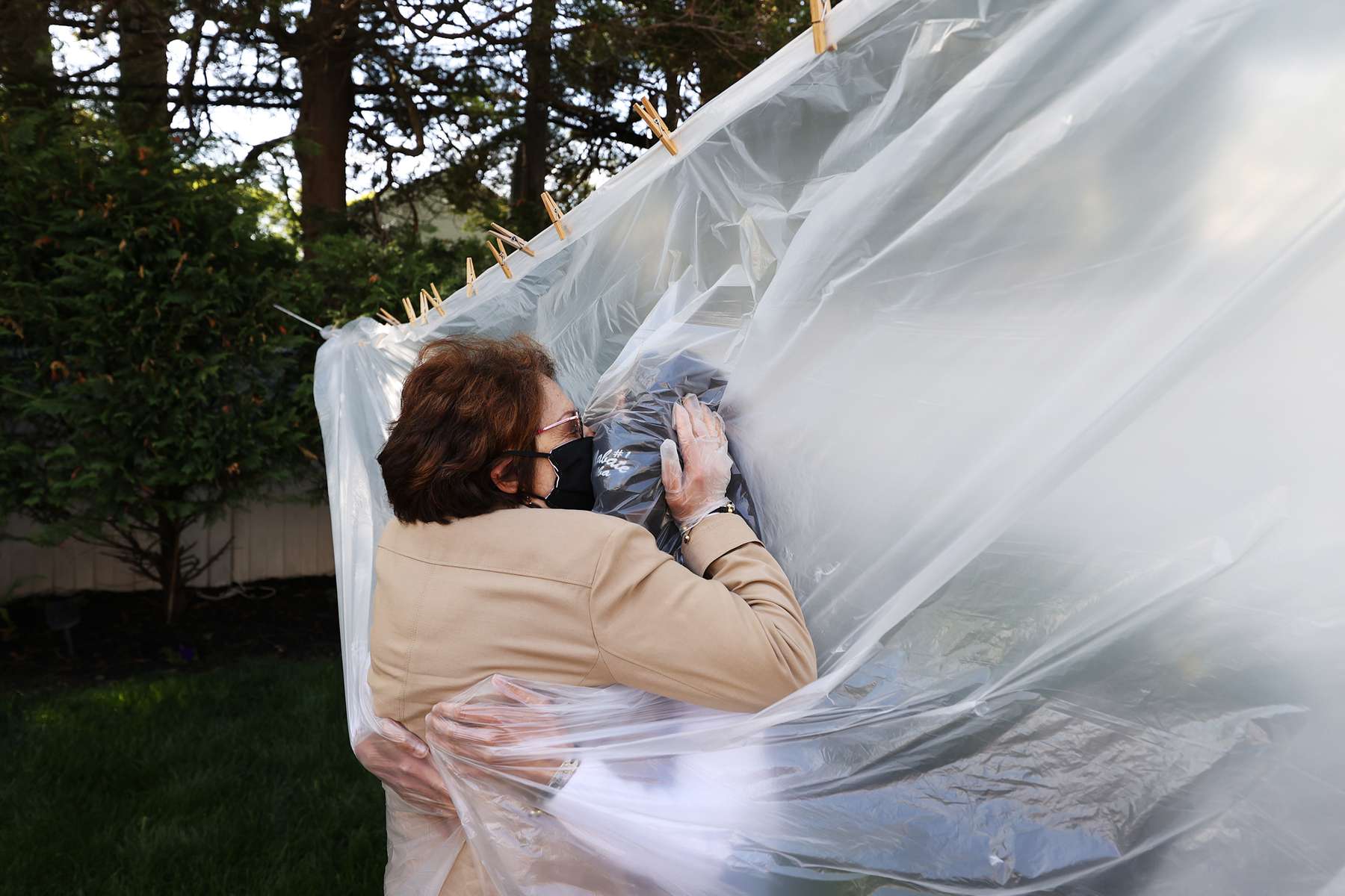 Michelle Grant hugs her Mother Mary Grace Sileo through a plastic drop cloth hung up on a homemade clothes line during Memorial Day Weekend on May 24, 2020 in Wantagh, New York.  It is the first time they have had physical contact of any kind since the coronavirus COVID-19 pandemic lockdown started in late February.  