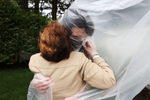 John Sileo hugs his Grandmother Mary Grace Sileo through a plastic drop cloth hung up on a homemade clothes line during Memorial Day Weekend on May 24, 2020 in Wantagh, New York.  It is the first time they have had contact of any kind since the coronavirus COVID-19 pandemic lockdown started in late February.  