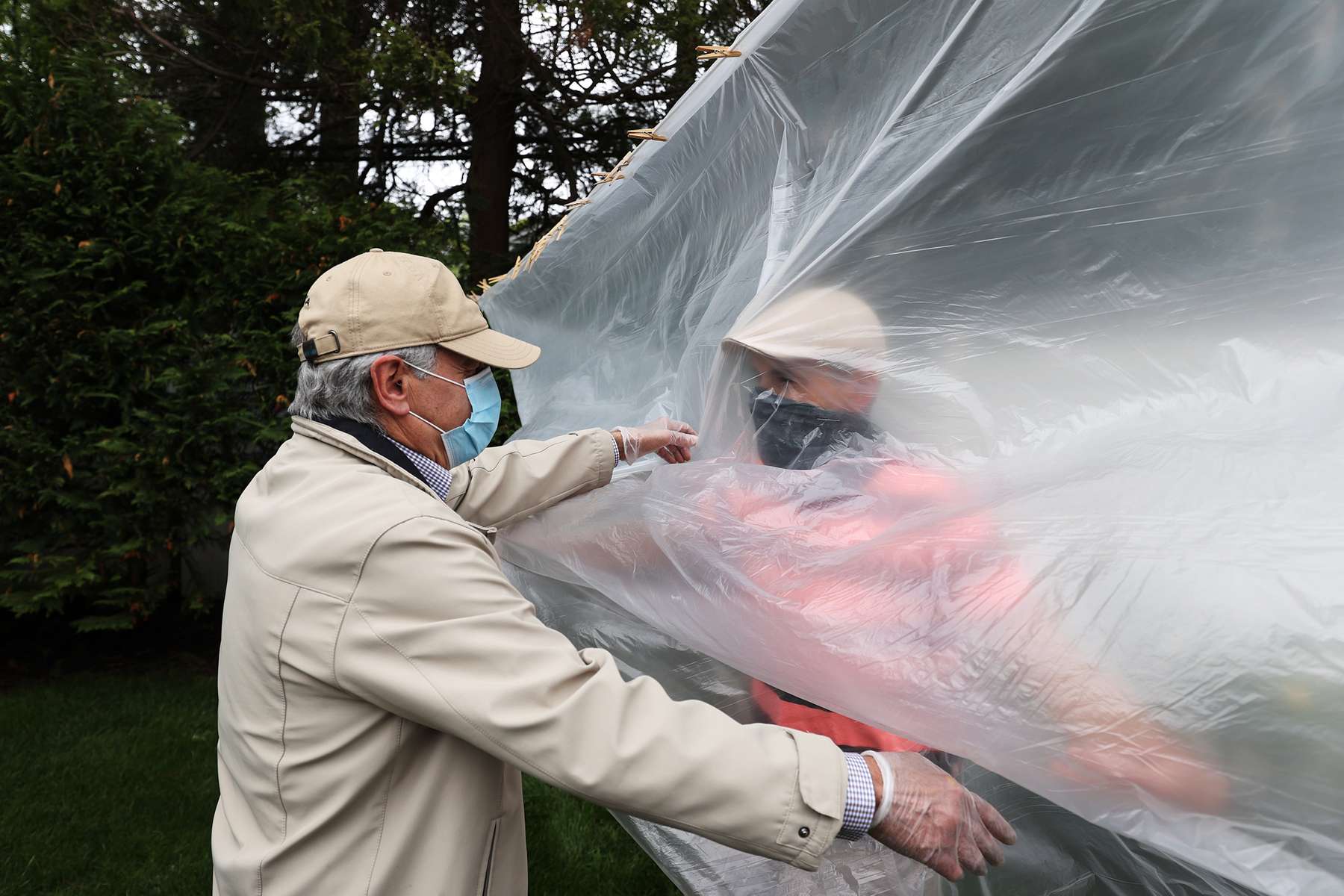 Frank Sileo hugs his Father Domenic Sileo through a plastic drop cloth hung up on a homemade clothes line during Memorial Day Weekend on May 24, 2020 in Wantagh, New York.  It is the first time they have had physical contact of any kind since the coronavirus COVID-19 pandemic lockdown started in late February.  