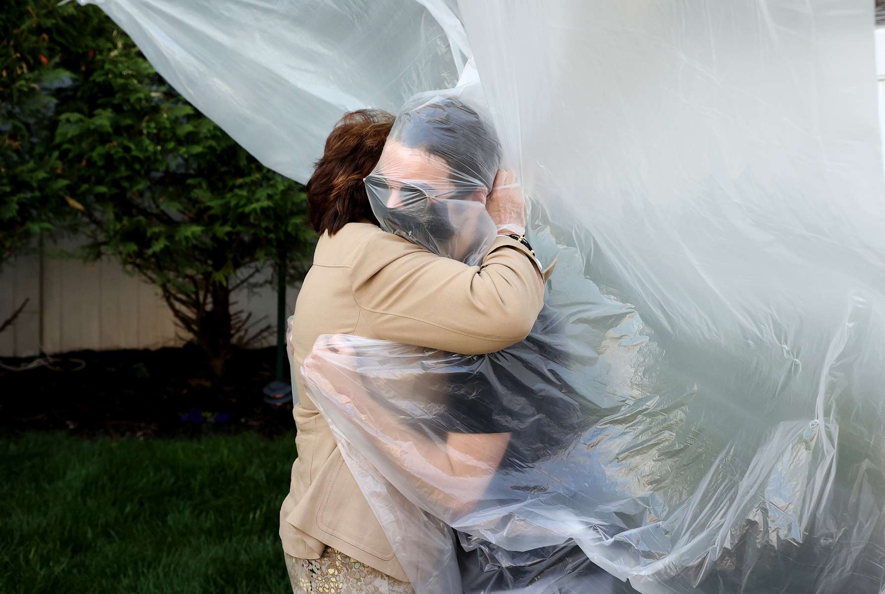 James Grant hugs his Grandmother Mary Grace Sileo through a plastic drop cloth hung up on a homemade clothes line during Memorial Day Weekend on May 24, 2020 in Wantagh, New York.  It is the first time they have had contact of any kind since the coronavirus COVID-19 pandemic lockdown started in late February.  