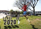 WANTAGH, NEW YORK - MAY 15:  John Sileo, Wantagh High School Co-President class of 2020 poses in front of a sign on the grass as graduating Seniors from Wantagh High School drive by the front of the school and their teachers cheer for them on May 15, 2020 in Wantagh, New York.  The school semester  has been cancelled and students had to finish their year with online video classes due to the coronavirus COVID-19 pandemic.  (Photo by Al Bello/Getty Images)