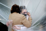 Olivia Grant hugs her Grandmother Mary Grace Sileo through a plastic drop cloth hung up on a homemade clothes line during Memorial Day Weekend on May 24, 2020 in Wantagh, New York.  It is the first time they have had contact of any kind since the coronavirus COVID-19 pandemic lockdown started in late February.  