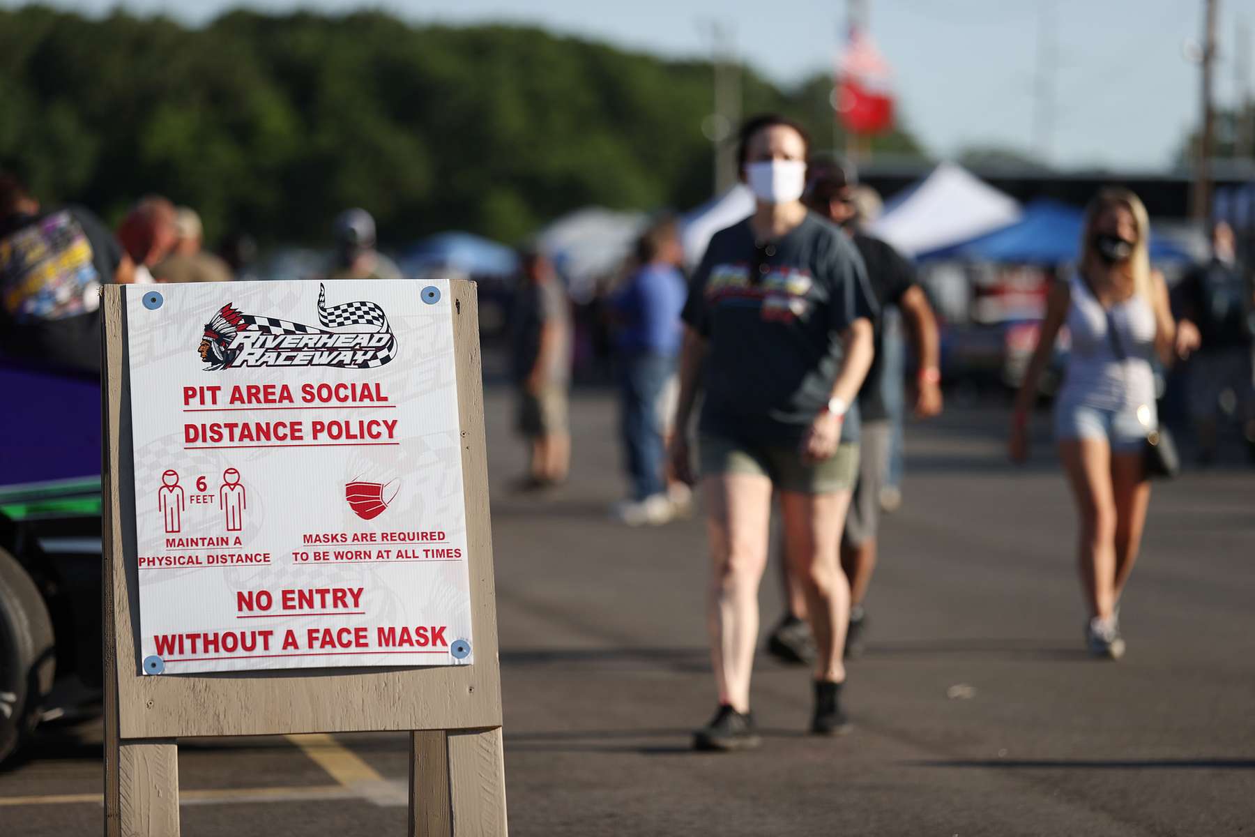 A sign is displayed promoting wearing a face mask and social distancing during NASCAR Advance Auto Series Opening Night  at Riverhead Raceway on August 01, 2020 in Riverhead, New York.  The race track had been closed due to the coronavirus COVID-19 pandemic.  More than 4,585,258 people in the United States alone have been infected with the coronavirus and at least 154,000 have died. 