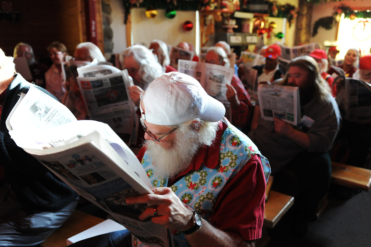 Student Santas hide their faces with a newspaper from the visiting children as not to confuse them while a dressed up Santa is performing during the Charles W. Howard Santa Claus School workshop on October 17, 2008 in Midland, Michigan.  