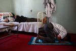 A medical staff prays while other staff members take a rest inside the doctor's office.  The medical staff's monthly income is 8400 Afghani, about US$168.00.  Being the sole government run hospital of its kind, patients come from everywhere nonstop, making it very busy.